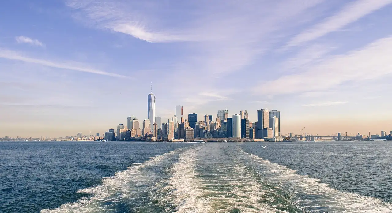 A boat's wake leading back toward the Manhattan skyline