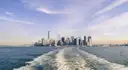 A boat's wake leading back toward the Manhattan skyline