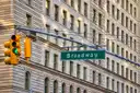 A green Broadway street sign and traffic light on a Manhattan corner