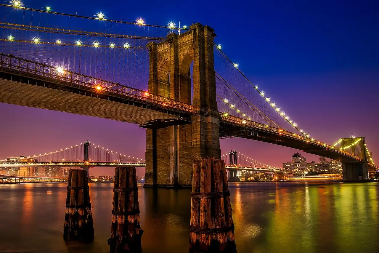 The Brooklyn Bridge lit up at night, seen from the East River