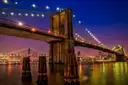 The Brooklyn Bridge lit up at night, seen from the East River