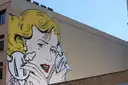 A comic-style pop-art mural of a woman on a Brooklyn wall