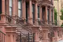 A row of brownstone houses with tall stone stoops