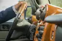 A driver in a suit with his hand on the steering wheel