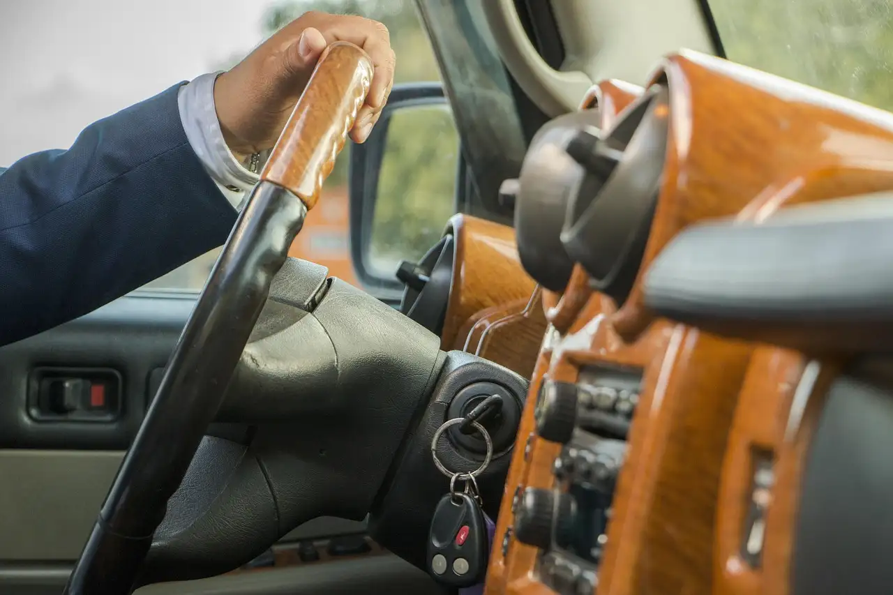 A driver in a suit with his hand on the steering wheel