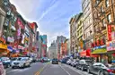 A Chinatown street in Manhattan with shop signs and parked cars