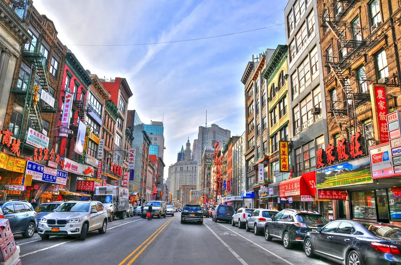A Chinatown street in Manhattan with shop signs and parked cars