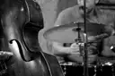 A double bass and drums on stage, in black and white