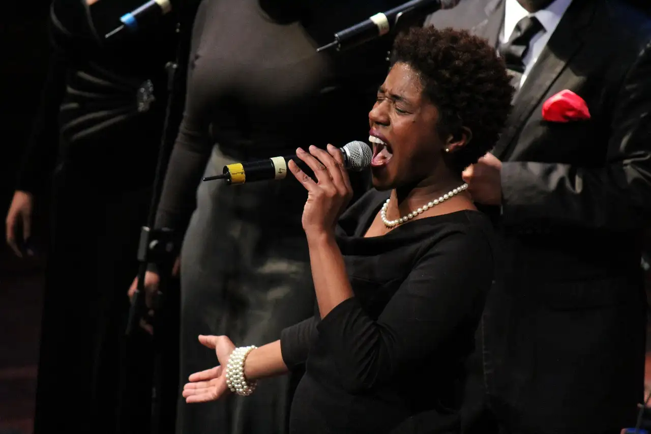 A gospel singer singing into a microphone on stage