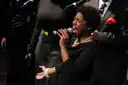 A gospel singer singing into a microphone on stage