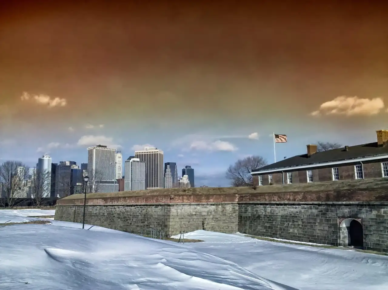 The stone walls of Fort Jay on Governors Island in snow, with Lower Manhattan across the water