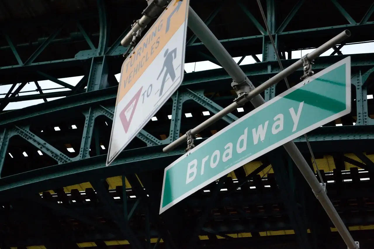 A Broadway street sign under the elevated subway line in Harlem