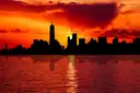 Lower Manhattan in silhouette against a red sunset
