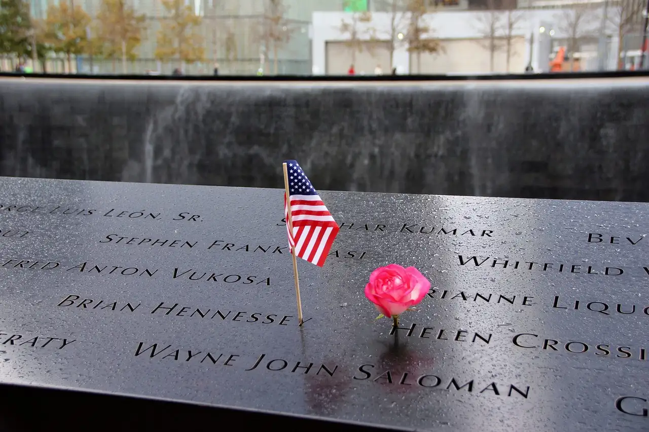 A small US flag and a rose in the names on the memorial