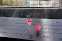 A small US flag and a rose in the names on the memorial