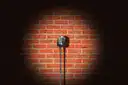 A vintage microphone in a spotlight against a brick wall