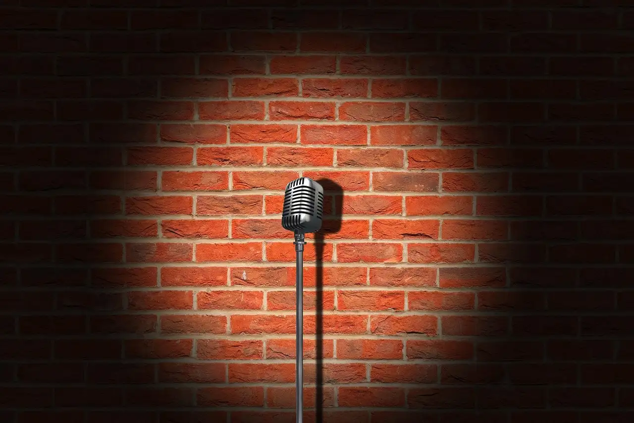 A vintage microphone in a spotlight against a brick wall