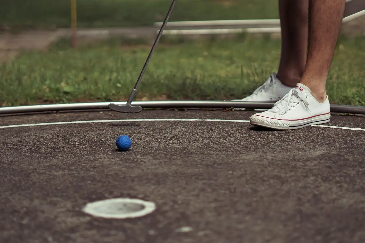 A putter and a blue ball on a mini-golf course