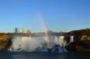 The American Falls at Niagara Falls with a rainbow in the spray and autumn trees on the bank