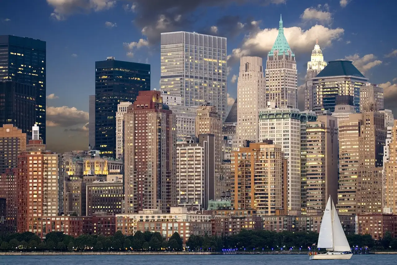 The Lower Manhattan skyline seen across the water, with a sailboat in front