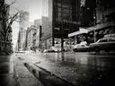 A wet Manhattan street after rain, with puddles and taxis, in black and white