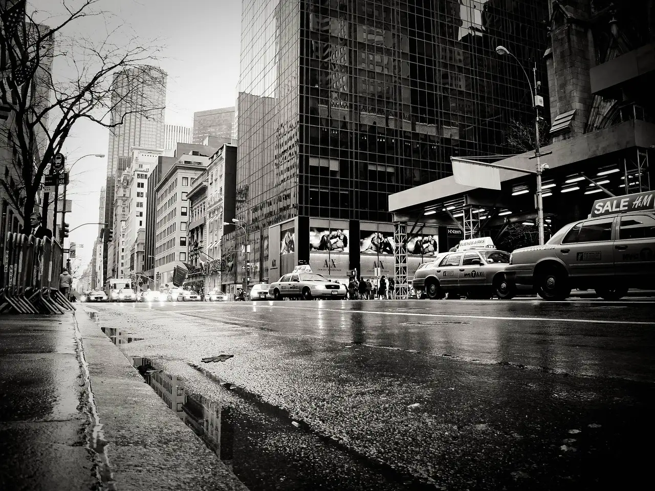 A wet Manhattan street after rain, with puddles and taxis, in black and white
