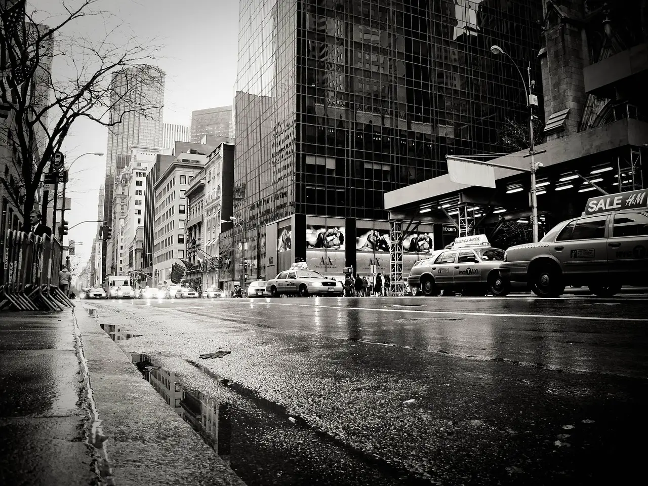 A wet Manhattan street after rain, with puddles and taxis, in black and white