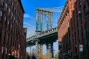 The Manhattan Bridge framed by red-brick warehouse buildings on Washington Street in DUMBO, Brooklyn