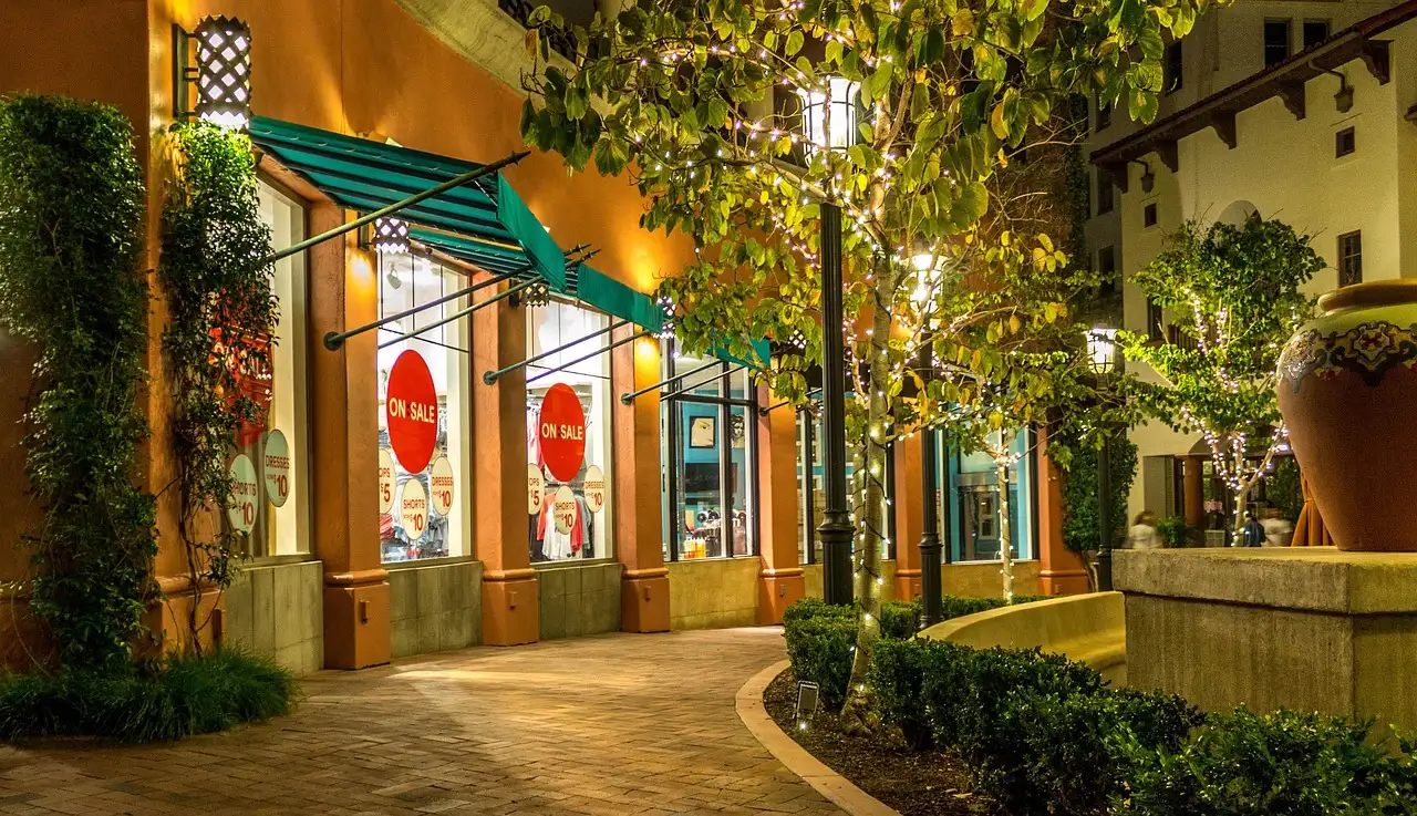 Open-air outlet shops with sale signs along a lit walkway