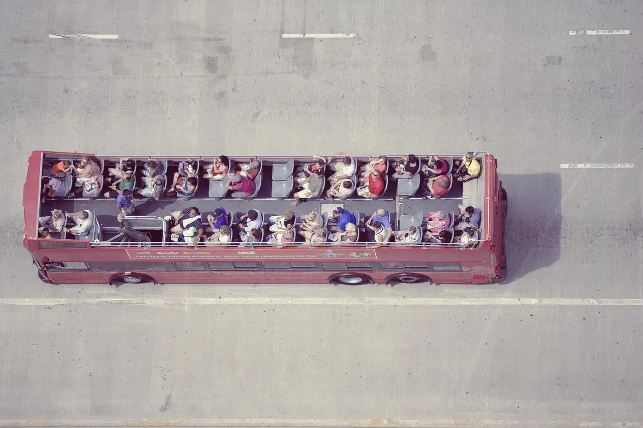 An open-top sightseeing bus full of riders, seen from above