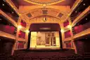 A gilded theatre stage seen from the balconies