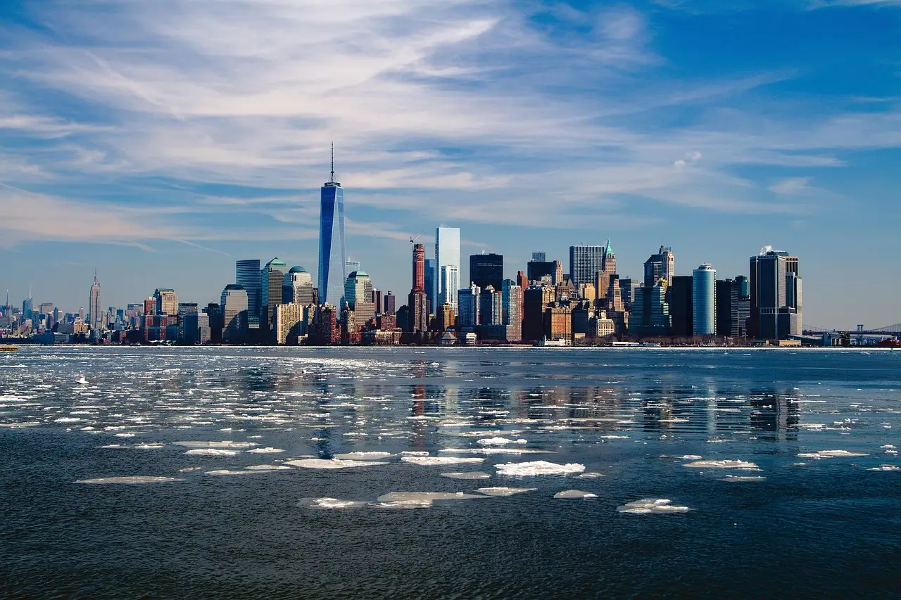 Lower Manhattan's skyline with One World Trade Center across the water on a clear winter day, with ice floating in front