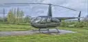 A small Robinson R44 helicopter on its landing pad
