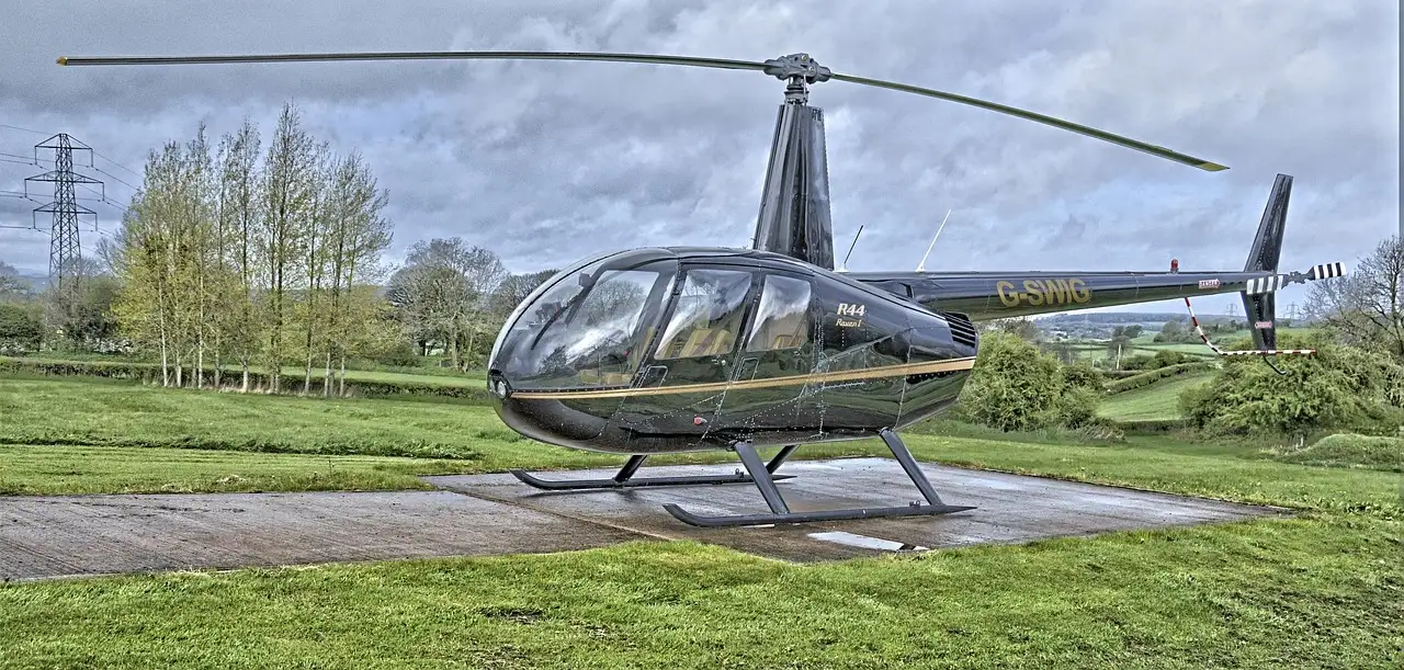 A small Robinson R44 helicopter on its landing pad