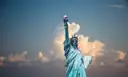 The Statue of Liberty against white clouds and blue sky