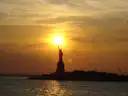 The sun setting behind the Statue of Liberty