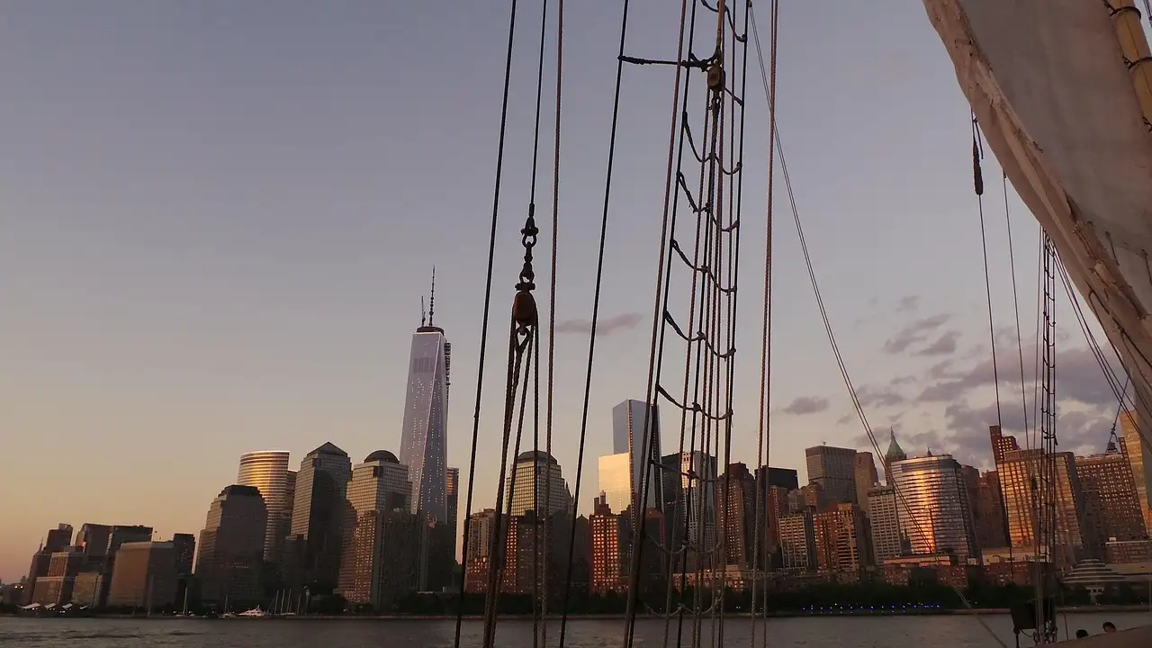 Lower Manhattan at dusk seen past a sailing ship's rigging
