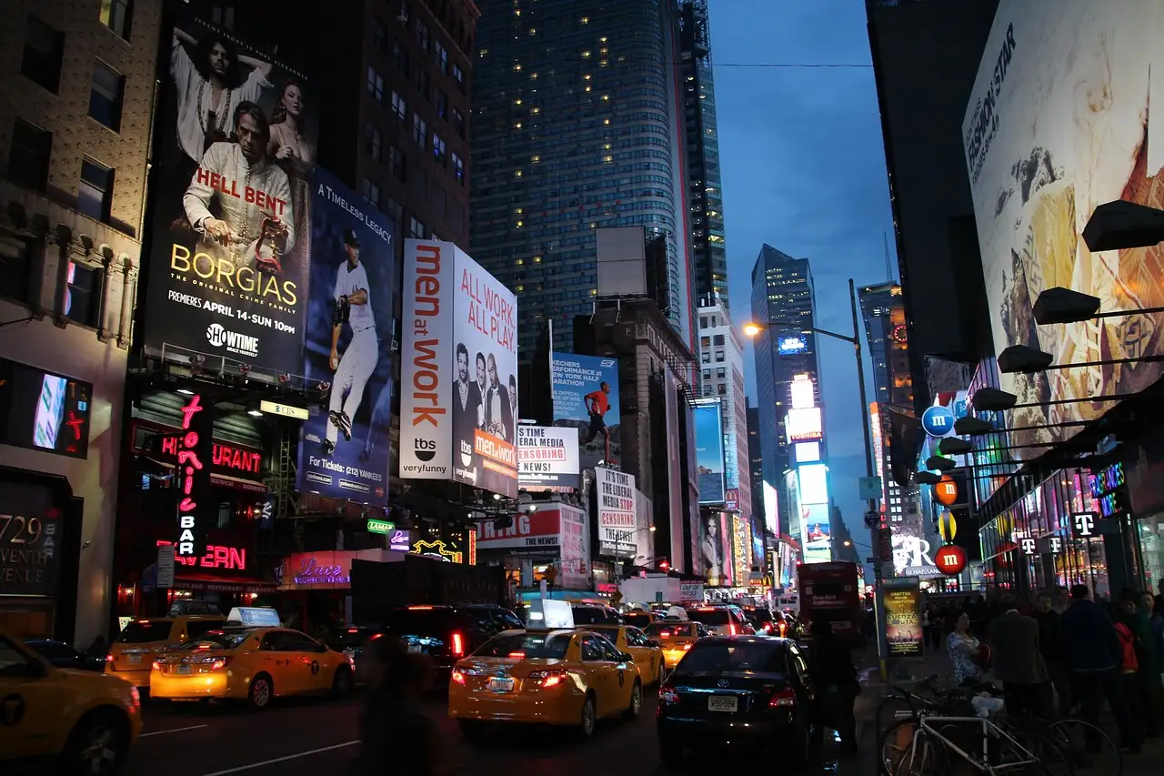 Times Square at dusk with the screens lit and taxis in the street