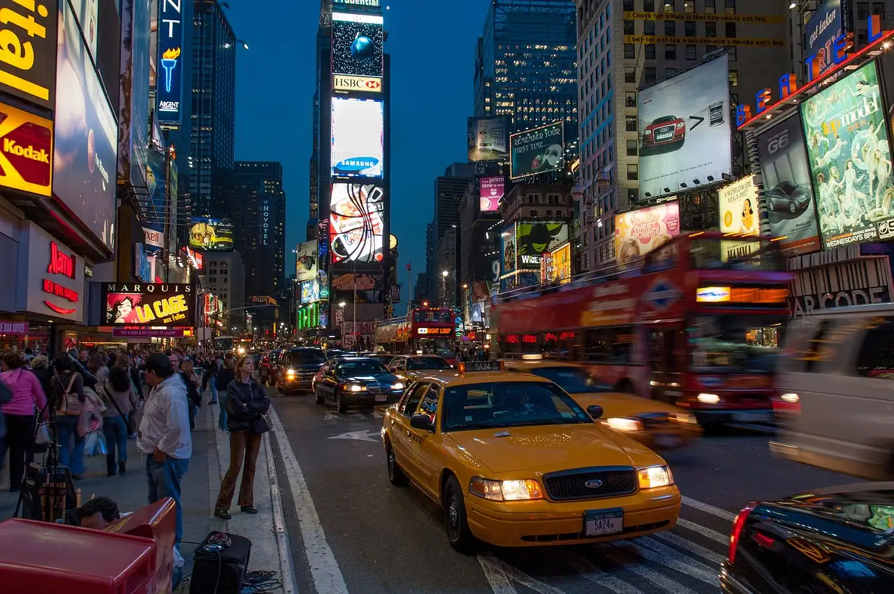 Times Square at dusk with a yellow cab, a short walk from the theatres on 42nd Street