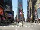 Times Square by day: a wide, quiet street between towers hung with billboards