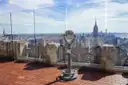 The Top of the Rock deck with a viewer, glass panels and the Empire State Building beyond