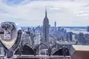 A coin-operated viewer on an observation deck, with the Empire State Building beyond